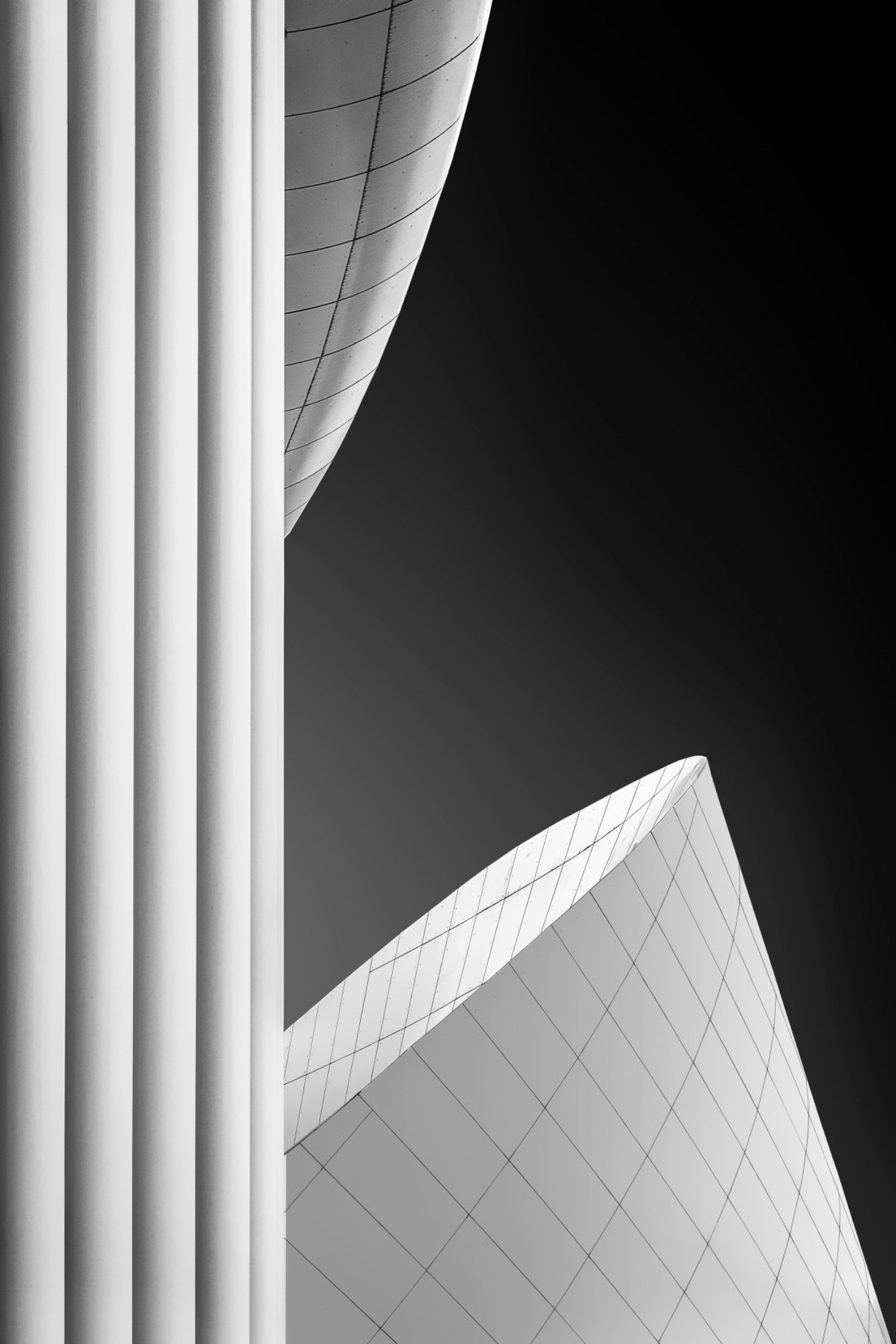 Moderne, geschwungene Architektur mit dunklem Himmel im Hintergrund.