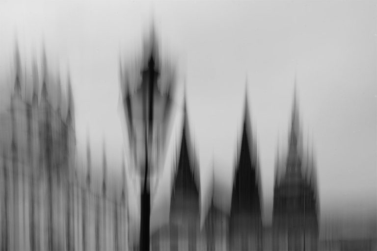 Unscharfe Silhouette von Türmen und einer Laterne im Vordergrund.