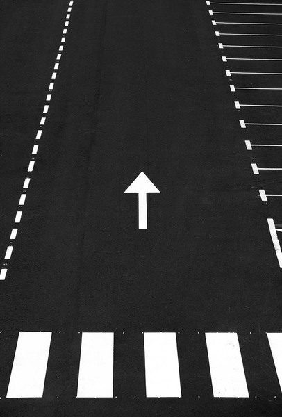 Parkerlinie mit einem weißen Pfeil, der nach oben zeigt, auf schwarzem Asphalt.