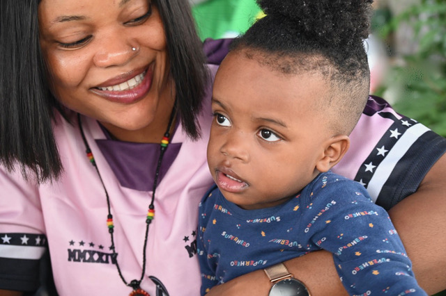 Mutterliebe Ein lächelnde Frau hält ein Kleinkind auf ihrem Schoß, beide schauen konzentriert.