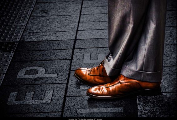 Elegante braune Schuhe stehen auf einem Gehweg mit Markierungen.